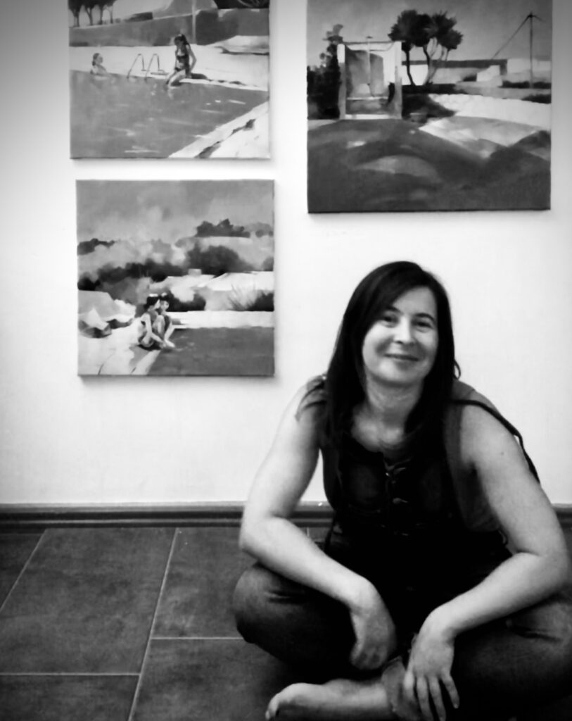 Artist with Finished Oil Paintings Artist sitting on the floor with three large oil paintings hanging on the wall in the background.