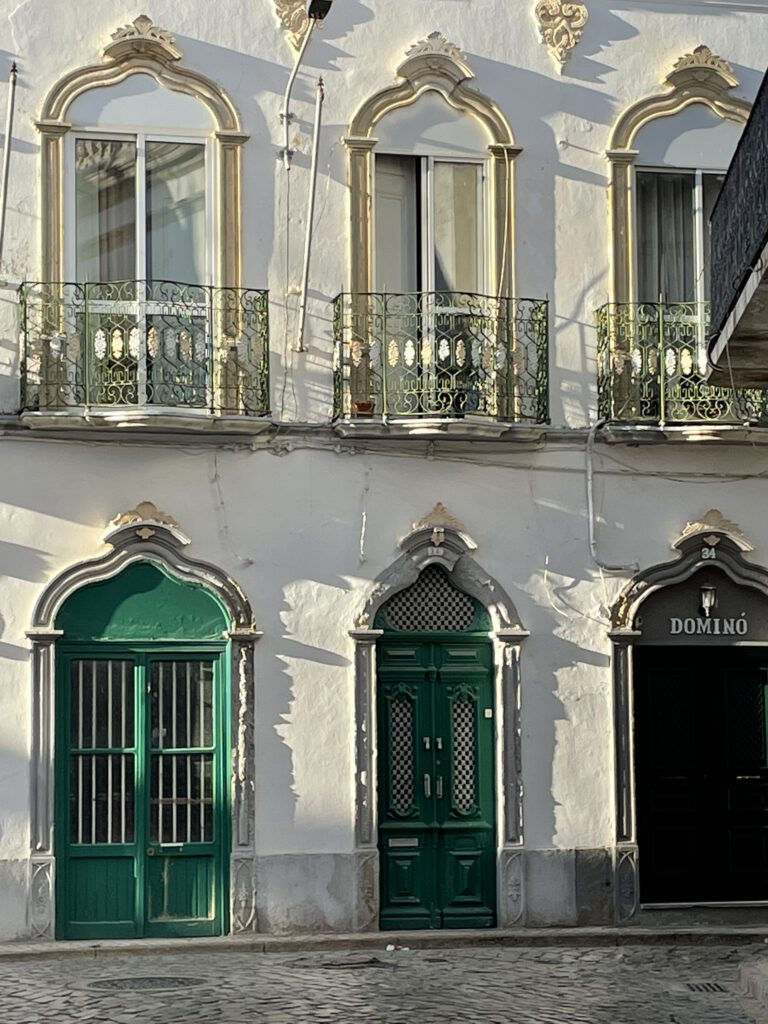 Art Nouveau Facade in Olhão Facade of an old house in Olhão with tall windows and decorative Art Nouveau-style doors, now home to a Domino's restaurant