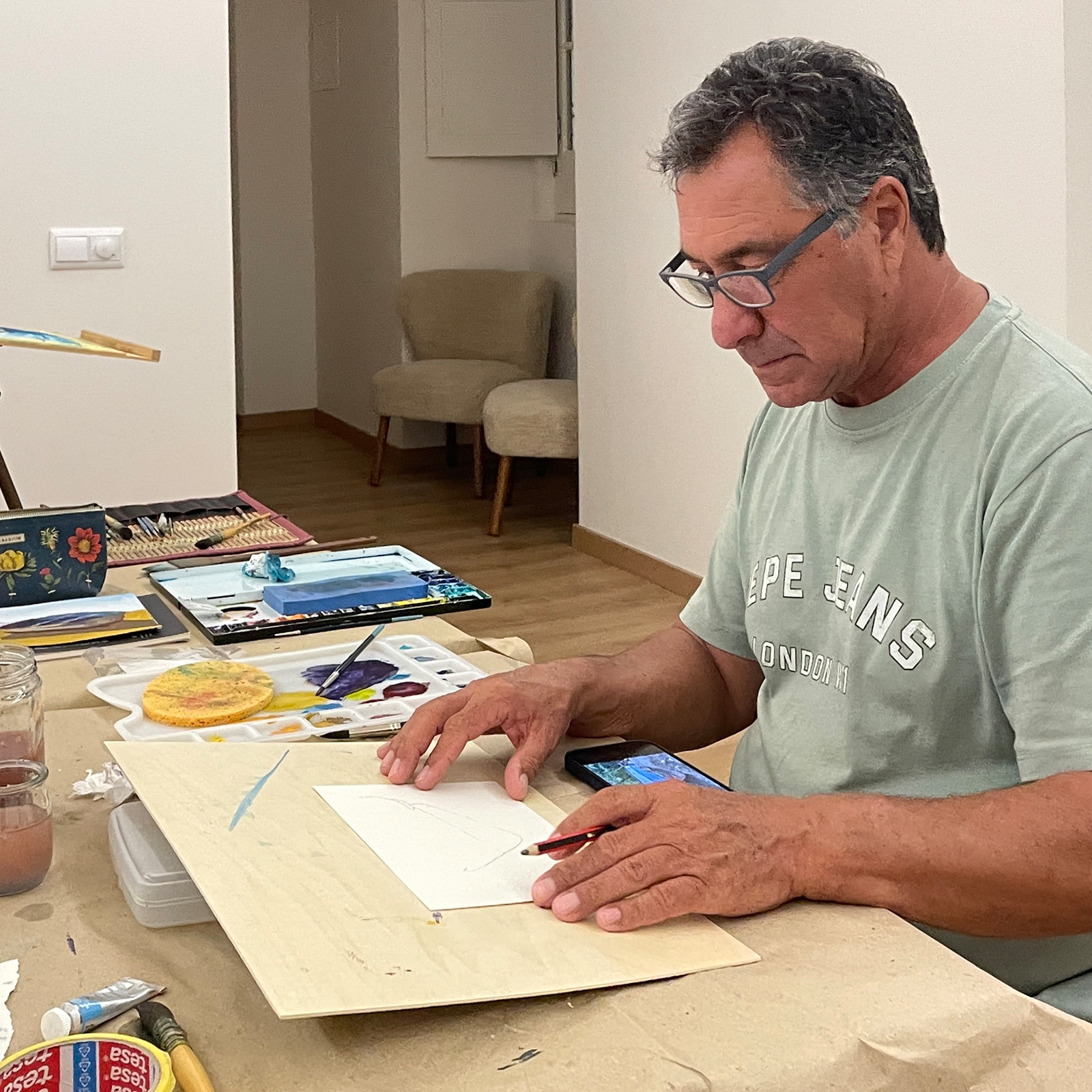 Man preparing to begin his watercolor painting during the “Barcas de Olhão” course in the Olhão art studio, with materials laid out on the table.