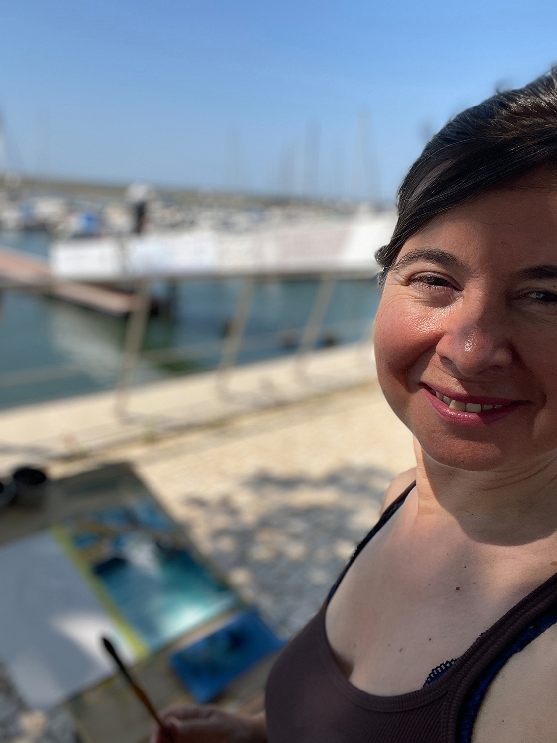 Grażyna Ostrowska holding one of her large Algarve-inspired paintings, introducing herself as the host of Lighthouse Artcourses.