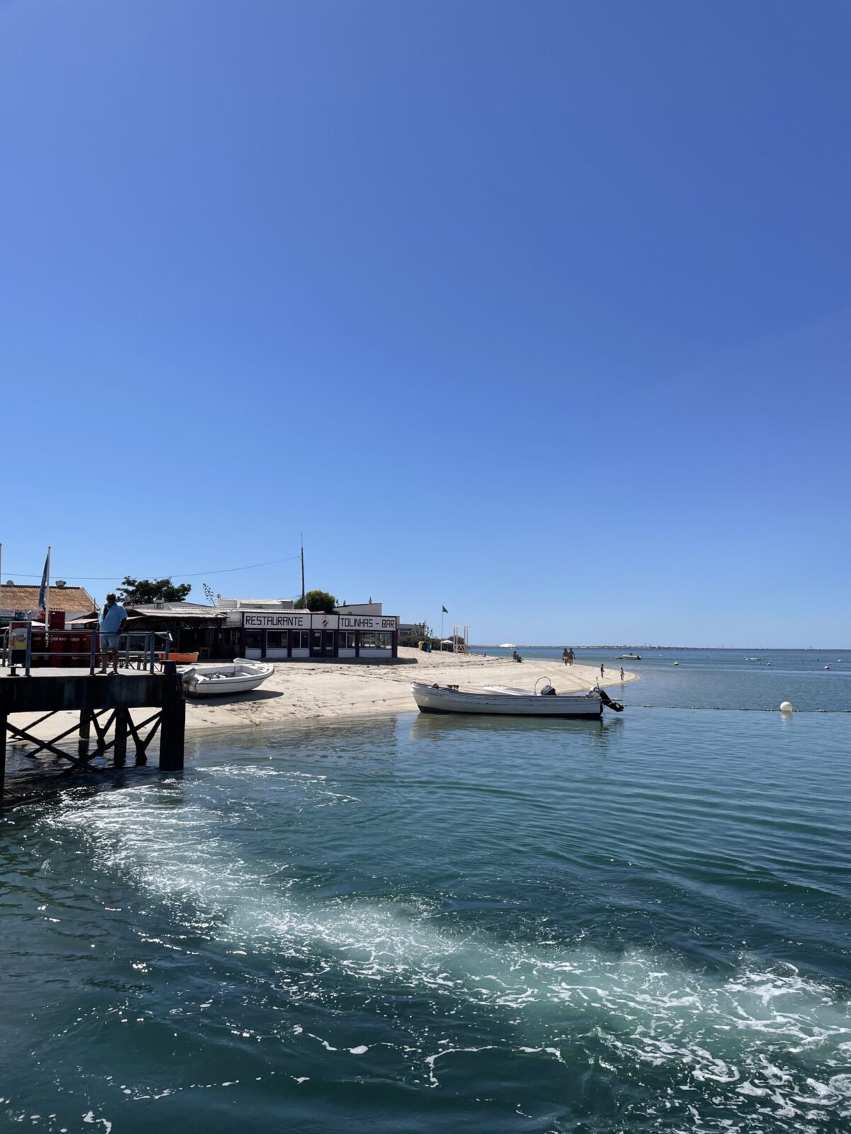View of the Armona ferry pier with sparkling sea water under bright sunlight.