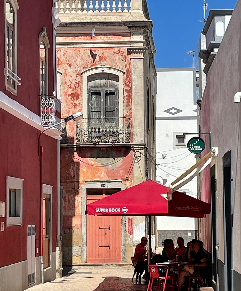Bright yellow entrance door in Olhão with traditional hand-shaped doorknobs