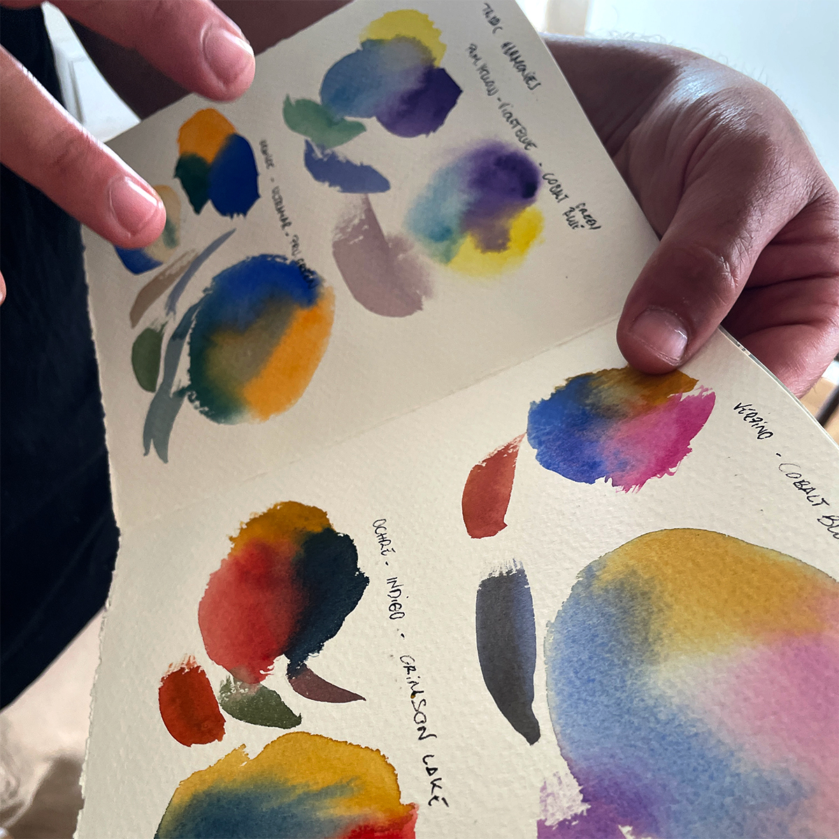 Close-up of watercolour pigments and painted paper representing the creative process behind Algarve art experiences